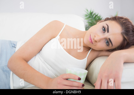 Erschöpfte junge Frau auf einer couch Stockfoto