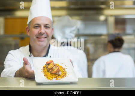 Erfahrene Reife Koch präsentiert eine Gericht Stockfoto