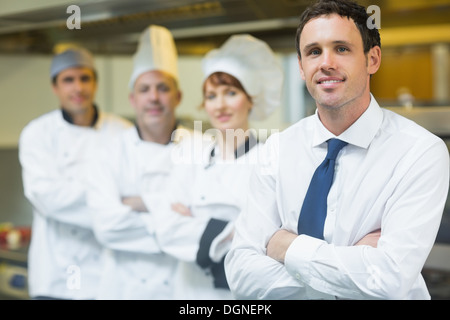 Junge Restaurantleiter posiert vor team Stockfoto