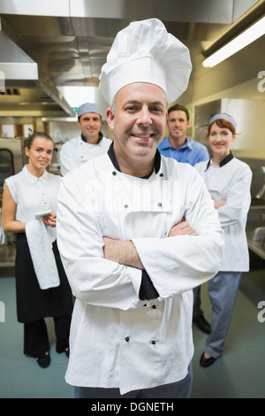 Küchenchef mit seinem Team hinter ihm posiert Stockfoto