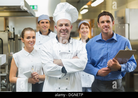 Chefkoch posiert mit dem Team hinter ihm Stockfoto