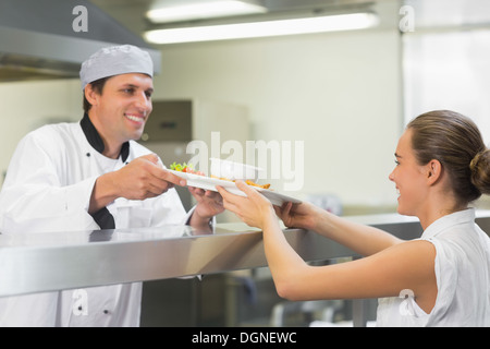 Übergabe einer Platte der Kellnerin glücklich Jungkoch Stockfoto