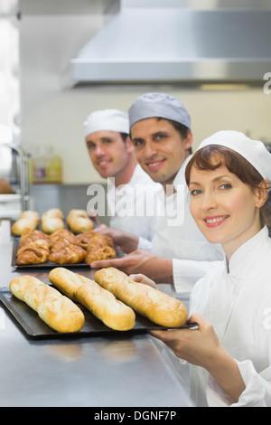 Drei junge Bäcker holding Backbleche Stockfoto