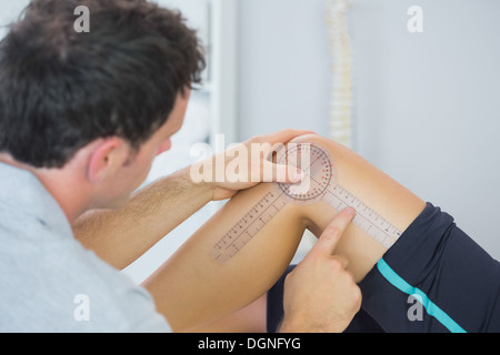 Physiotherapeut Überprüfung Knie mit Winkelmesser Stockfoto