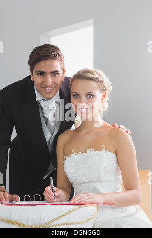 Junge Ehepaar sitzt am Tisch, die Unterzeichnung Hochzeit Register Stockfoto