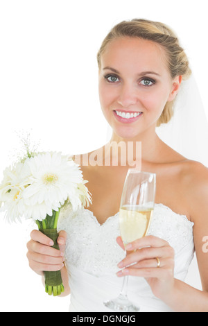 Fröhliche Braut hält einen Blumenstrauß und ein Glas Champagner Stockfoto