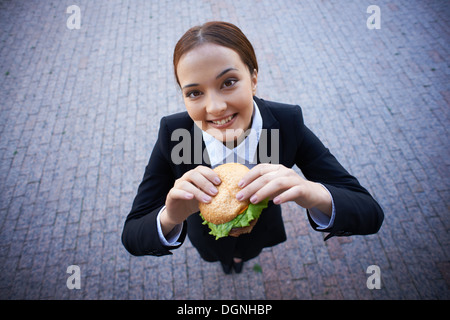 Geschäftsfrau mit Blick in die Kamera außerhalb sandwich Stockfoto
