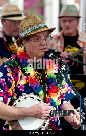Ein Mann singt und spielt eine Banjo Ukulele, Teil einer Ukulele-Band. Stockfoto