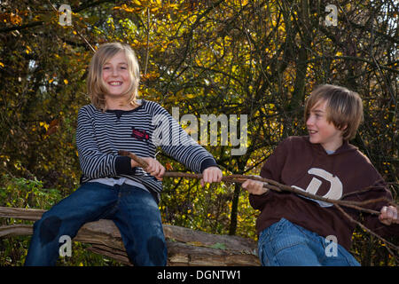 Zwei Jungen spielen im Wald mit einem Ast Stockfoto