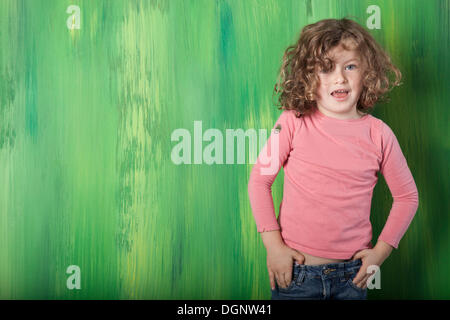 Rothaarige Mädchen, 5 Jahre alt, steht man vor einer grünen Wand Stockfoto