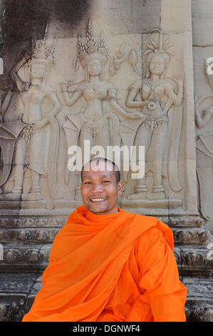 Buddhistischer Mönch im Zentrum von Angkor Wat sitzt vor einem Relief Darstellung Apsara aus der hinduistischen Mythologie, Kambodscha Stockfoto