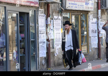 Straßenszene mit ein orthodoxer Jude im Bezirk Me'a She'arim mit typischen Häusern und Wandzeitungen, Jerusalem, Israel Stockfoto