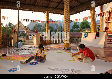 Handwerker, die Malerei Deckenplatten auf dem Boden von einem buddhistischen Tempel, Vang Vieng, Laos, Südostasien Stockfoto