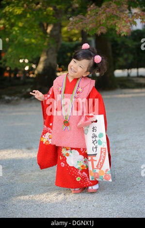 Shichi-Go-San, sieben-fünf-drei Festival, Mädchen in einem roten Kimono hält eine lange Tasche mit Süßigkeiten Stöcke, Chitose-Ame, stehend auf der Stockfoto