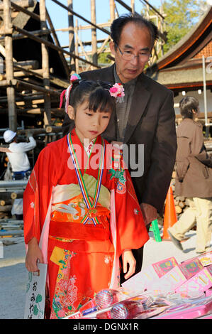 Shichi-Go-San, sieben-fünf-drei Festival, ein Vater und seine Tochter in einem roten Kimono, der hält eine lange Tasche mit Zuckerstangen Stockfoto