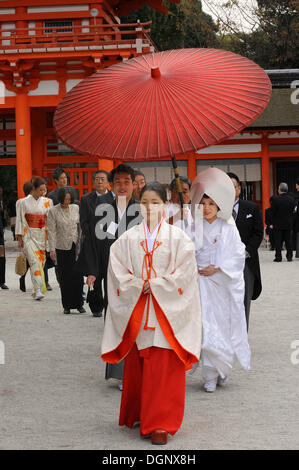 Japanische Frau mit scharlachroten Hakama Hosen und einem weißen Kimono Shirt mit langen Ärmeln, vor dem Torhaus von Stockfoto