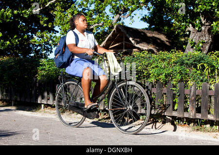 Mädchen in Schuluniform auf dem Fahrrad auf dem Weg zur Schule, La Digue, Seychellen, Afrika, Indischer Ozean Stockfoto