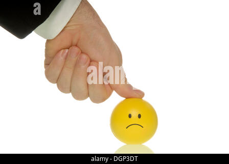 Geschäftsmann seinen Daumen drücken auf einen Smiley, symbolisches Bild für Leistungsdruck Stockfoto