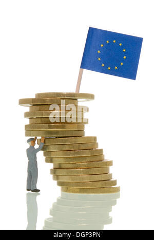 Arbeiter-Figur, die Schlusslichter bilden einen wackeligen Stapel von Euro mit einer europäischen Flagge auf Top, symbolische Bild, Euro-Krise Auswirkungen auf die Arbeit Stockfoto