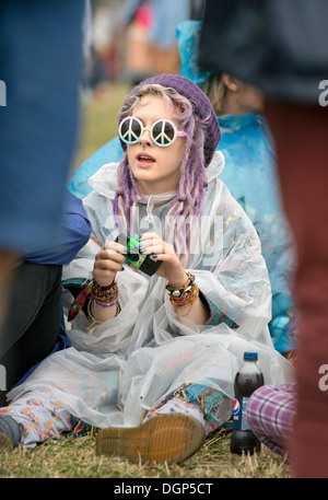 Das Reading Festival - ein Mädchen in einem Plastik Poncho mit CND Sonnenbrille Aug 2013 Stockfoto