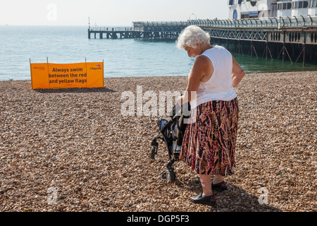 England, Hampshire, Portsmouth, Southsea, Southsea Strand, ältere Dame mit Kinderwagen am Strand Stockfoto