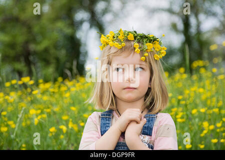 Mädchen tragen einen Blumenkranz auf dem Kopf, mit gefalteten Händen und eine Befragung aussehen, Porträt Stockfoto