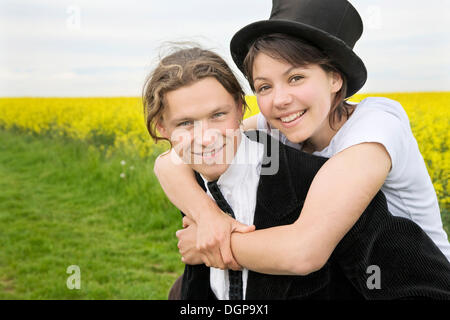 Junge Frau mit Hut, umarmt ihr Freund, der ihr auf seinem Rücken trägt Stockfoto