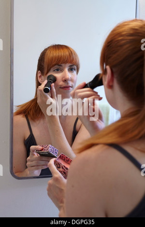 Mitte Erwachsene Frau Anwendung Rouge im Spiegel Stockfoto