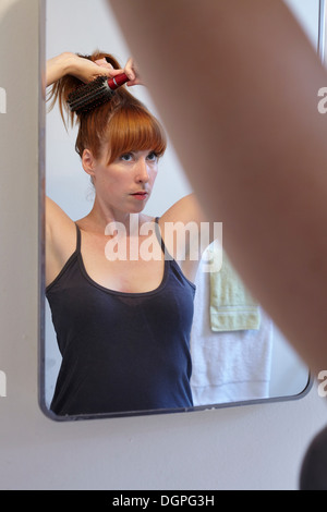 Mitte Erwachsene Frau Bürsten Haare im Spiegel Stockfoto