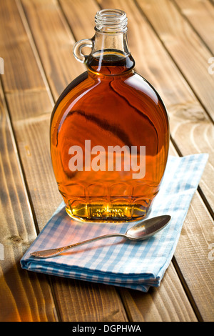 Ahornsirup in Glasflasche auf Holztisch Stockfoto