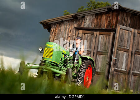 Mann mit einer Beinprothese einen Oldtimer-Traktor fahren Stockfoto