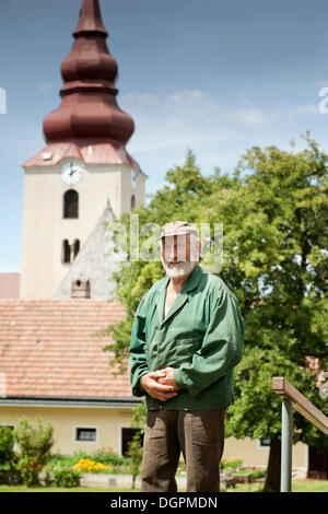 Greis, Landwirt steht man vor einer Kirche Stockfoto