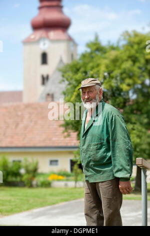 Greis, Landwirt steht man vor einer Kirche Stockfoto