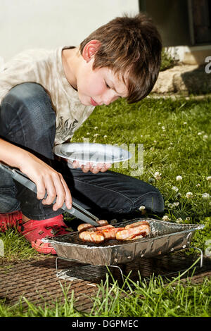 Junge mit einem Einweg-Grill Stockfoto