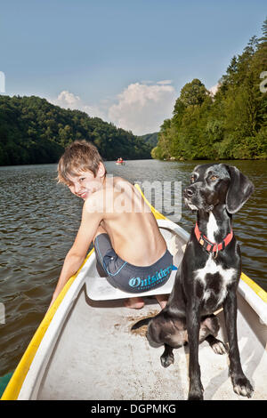 Junge sitzt in einem Kanu mit seiner Jagd Hund, Mischling Stockfoto