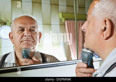 Älterer Mann mit einen elektrischen Rasierer Stockfoto