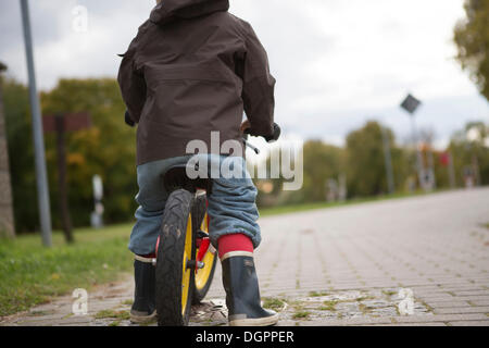 Ein kleiner Junge ist üben, um ein Fahrrad in einer ruhigen Straße, Brandenburg Stockfoto