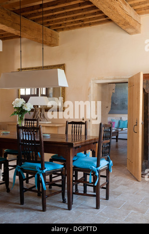 Rustikale Deckenbalken und Steinboden Fliesen in einem Speisesaal mit Holztisch und Stühle Stockfoto
