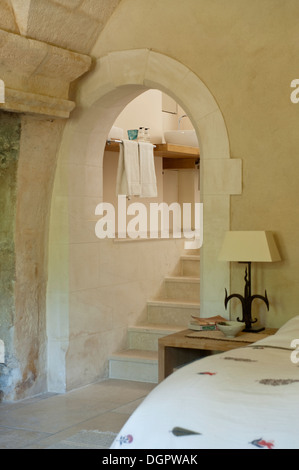 Schlafzimmer mit steinernen Torbogen mit Treppe, die zu einem Badezimmer Stockfoto