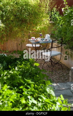 Schmiedeeisen-Café-Tisch und Stühle für Tee im Garten im Innenhof gelegt. Stockfoto