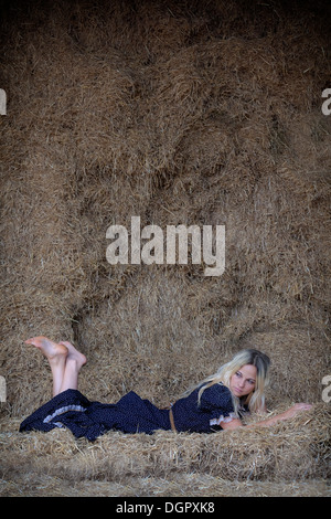 eine blonde Frau ist im Heu liegen. Stockfoto