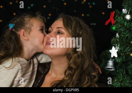 Kleines Mädchen küssen ihre Mutter in der Weihnachtszeit Stockfoto