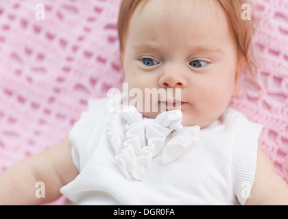 Das Baby liegt auf einem rosa Handtuch. Sie ist in rosa Shorts und eine weiße Bluse. Stockfoto