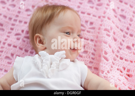 Das Baby liegt auf einem rosa Handtuch. Sie ist in rosa Shorts und eine weiße Bluse. Stockfoto