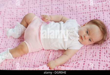 Das Baby liegt auf einem rosa Handtuch. Sie ist in rosa Shorts und eine weiße Bluse. Stockfoto