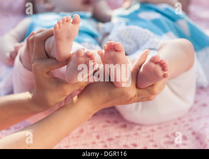 Beine Neugeborene in der Hand der Eltern. Zwillinge auf eine rosa Decke liegen. Stockfoto