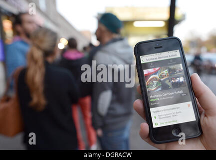 Berlin, Deutschland. 22. Oktober 2013. Eine Frau hält eine Smartphone die app von der Reise-Website "TripAdvisor", der empfiehlt, die Snack-Bar im Hintergrund, in Berlin, Deutschland, 22. Oktober 2013 anzeigen. Foto: BERND VON JUTRCZENKA/Dpa/Alamy Live-Nachrichten Stockfoto