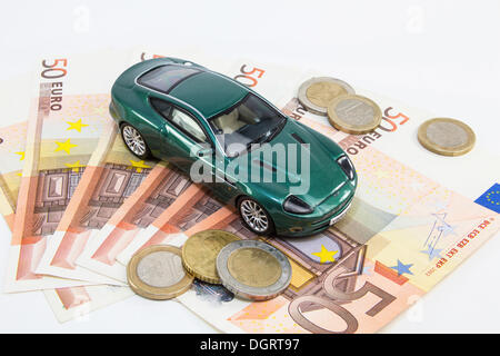 Spielzeugauto mit Euro-Banknoten und Euro-Münzen, symbolisches Bild für Luxussteuer auf teure Autos Stockfoto