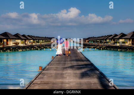 Touristen auf einem Steg Wasserbungalows auf Paradise Island, Lankanfinolhu, Nord-Malé-Atoll, Malediven Stockfoto