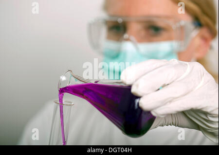 Chemiker Gießen eine Flüssigkeit aus einer Flasche in einem Reagenzglas Stockfoto